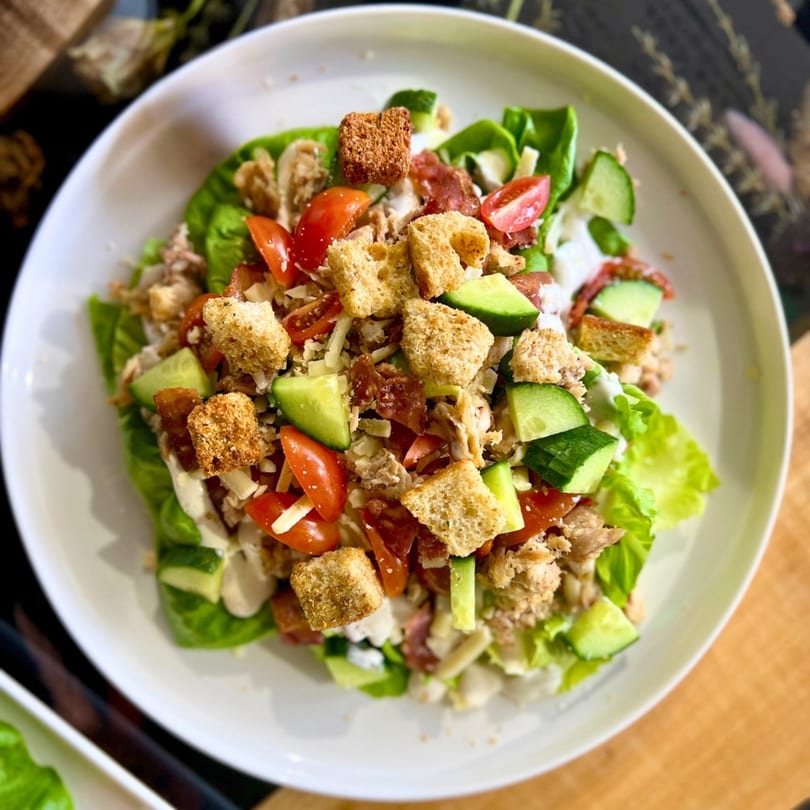 Feast and Graze cafe salad with lettuce, tomatoes, cucumbers, croutons, and chicken.